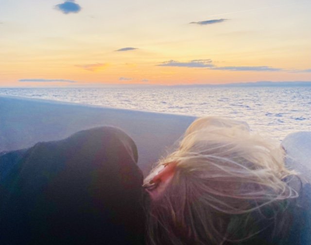 Una pareja se disfruta de una copa de vino durante una puesta de sol en un catamarán privado en Barcelona.