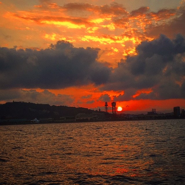 Una velero en el mar con la puesta de sol en el fondo