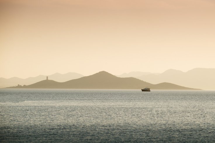 Bajo el atardecer, un barco navega por el Mar Menor