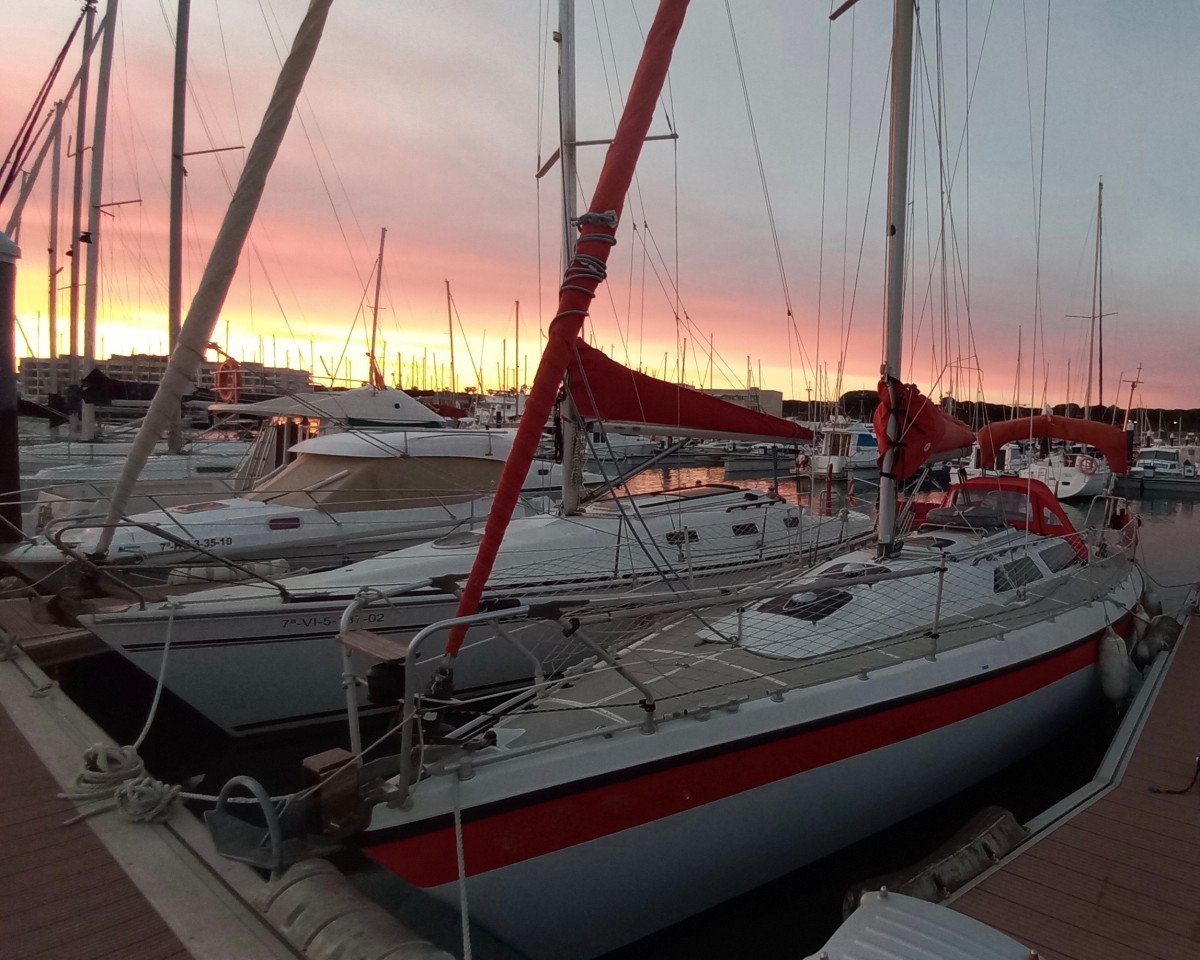 Una velero con las velas desplegadas en la Bahía de Cádiz durante la puesta del sol.