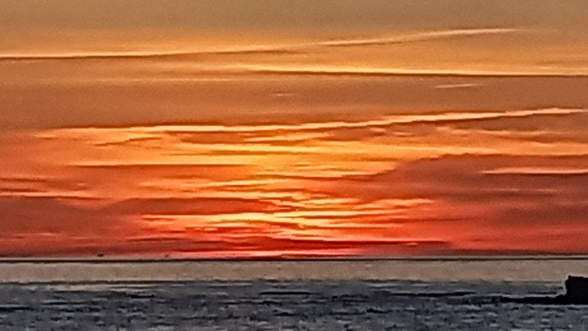 A sailboat drifting in the Bay of Cadiz during sunset.