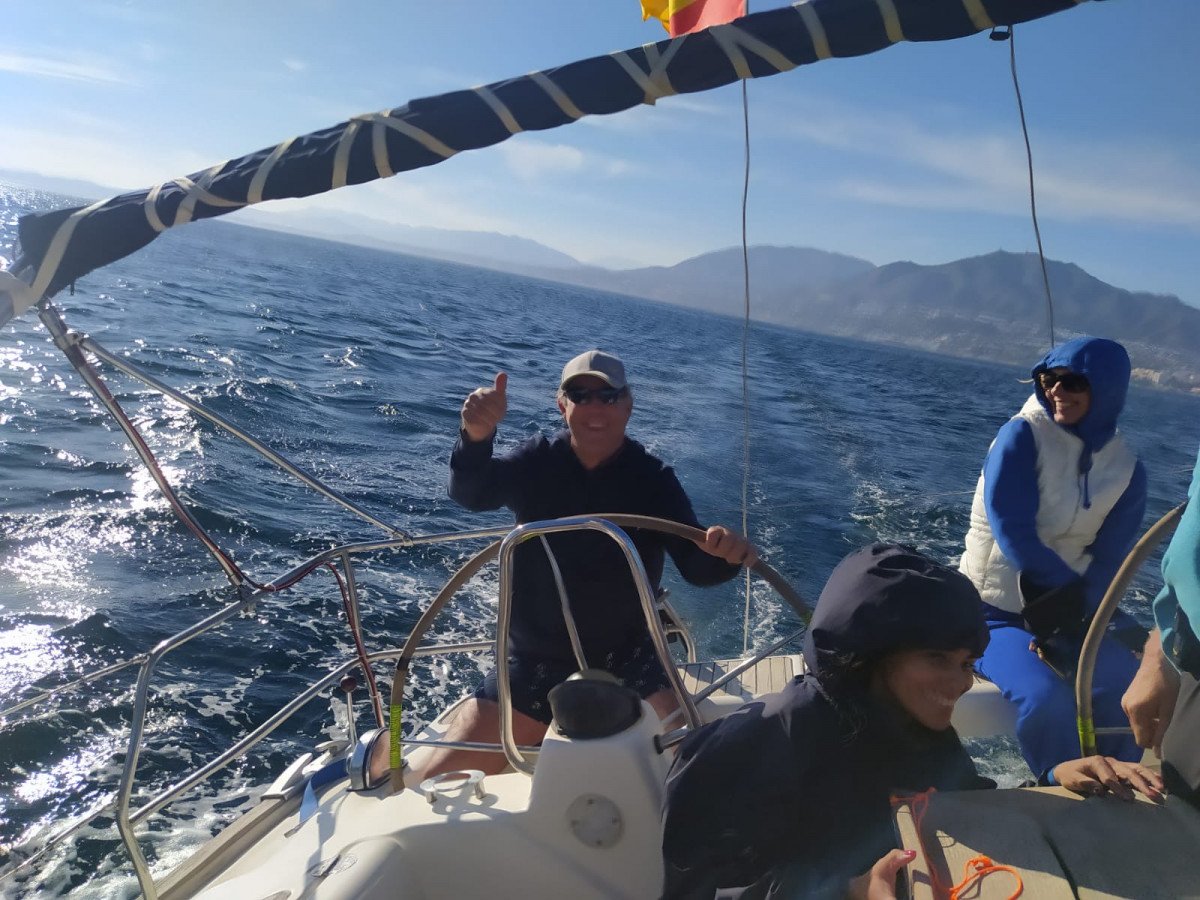 Una donna che impara a navigare su una barca a vela, sorridendo di orecchio a orecchio