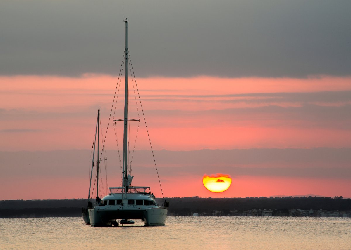 Amigos y familiares disfrutan de una puesta de sol en un viaje en catamarán en Barcelona.
